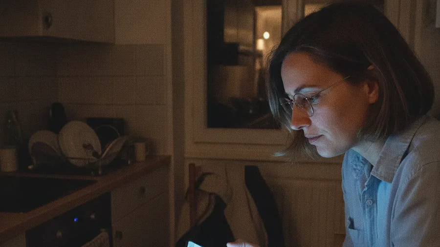 Valérie le soir dans sa cuisine, en train de lire un long article sur son téléphone