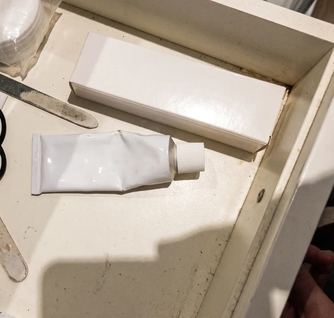Un tiroir de salle de bain ouvert : un tube à moitié pressé posé à côté de sa boîte de rechange encore fermée.